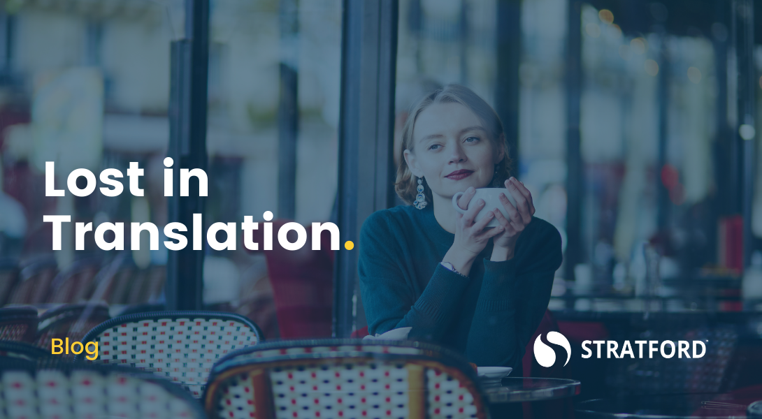 Worldly women sitting alone in Parisienne cafe looking thoughtful as she sips coffee. Text overlay "Lost in Translation."